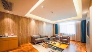 A modern living room with a sofa, armchairs, a coffee table, and a wooden floor.