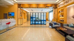 A modern lobby with a reception desk, seating area, and a large glass partition with a scenic view.