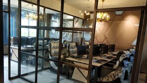 A modern office space with glass partitions, a central table, and a patterned sofa.