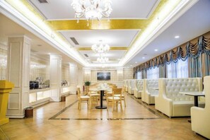 Rebedor d'hotel amb taulell de recepció, zona de seients i un penjallum.