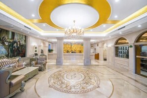 A luxurious lobby with ornate furniture, a grand chandelier, and a central decorative floor design.