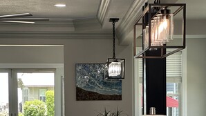 Eine moderne Küche mit Marmorarbeitsplatte, Pendelleuchten und einem großen Gemälde an der Wand.