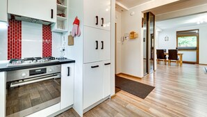 A modern kitchen with white cabinetry, a built-in oven, and a red-tiled backsplash. - Karpacz Boczna by Interhome (Karpacz)