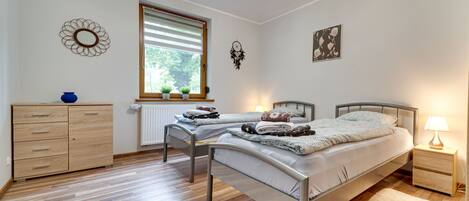 Un dormitorio con dos camas individuales, un aparador de madera, una ventana con persianas y un reloj de pared.