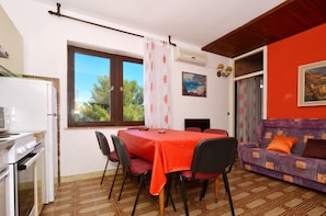 A dining area with a table and chairs, a sofa, and a kitchen area with a refrigerator and stove.