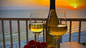 Une vue sur le coucher de soleil, avec deux verres de vin blanc et une bouteille, sur un balcon.