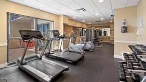 A gym with treadmills, elliptical machines, and dumbbells.