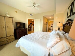 A hotel room with a bed, a TV, a wardrobe, and a ceiling fan.