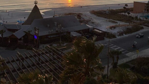A coastal sunset view with buildings and a road in the foreground.
