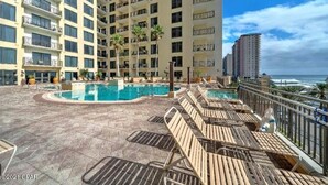 A rooftop pool area with lounge chairs, a pool, and a view of the ocean.