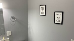 Een badkamer met toilet, wastafel en twee ingelijste motiverende borden aan de muur.