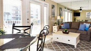 A living room with a sofa, coffee table, and a dining area with a table and chairs.