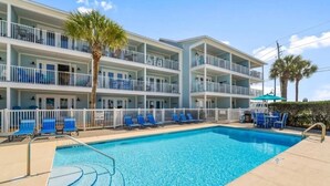 A multi-story hotel with a swimming pool, balconies, and lounge chairs.