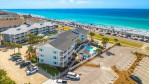 A coastal hotel with multiple floors, a swimming pool, and a beach view.