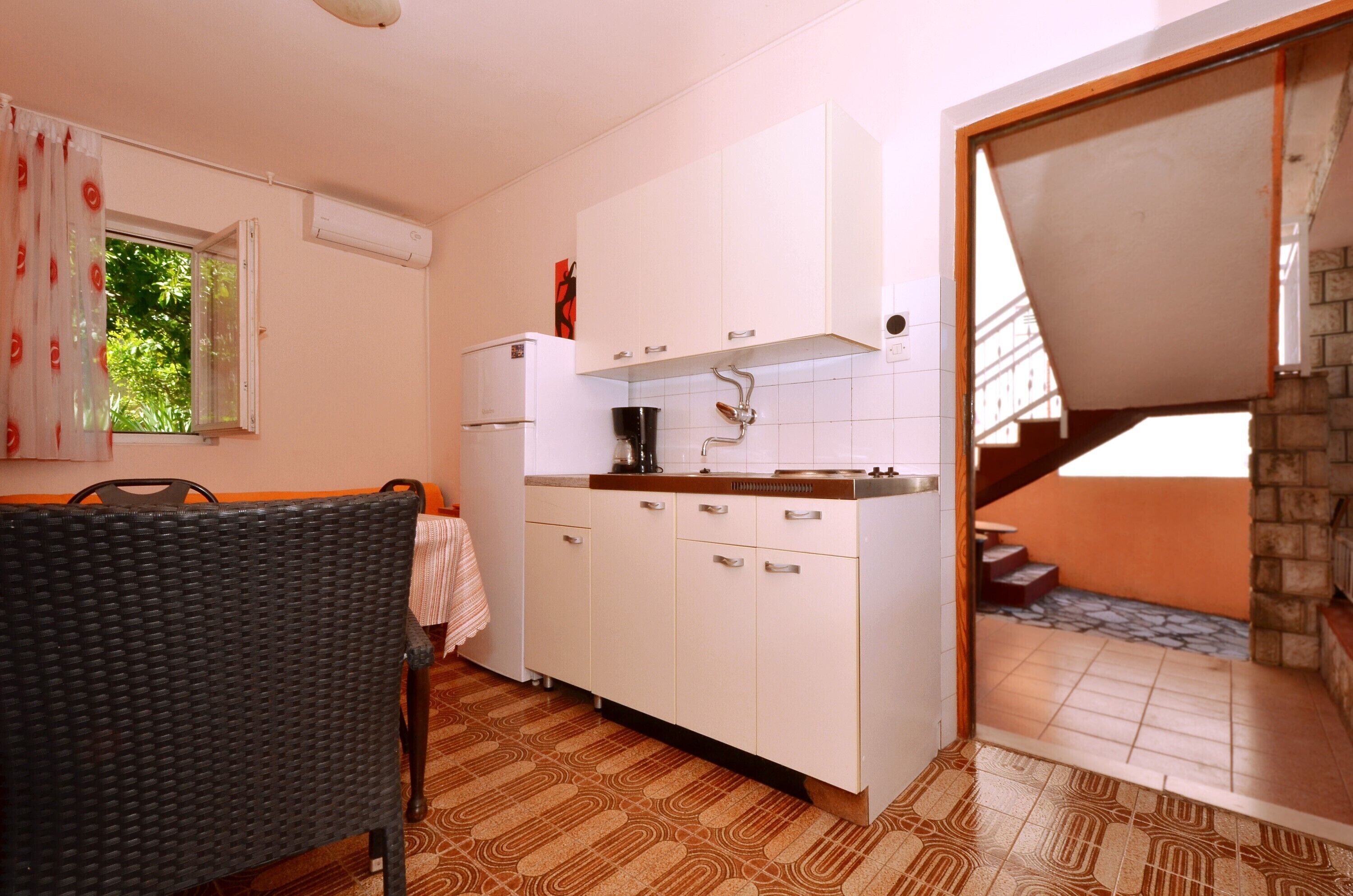 A kitchen with white cabinets, a coffee machine, and a window with a view of greenery.