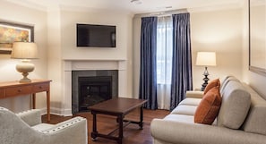 A living room with a fireplace, a television mounted on the wall, and a sofa with cushions.