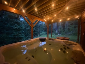 Ein Whirlpool mit Holzboden und Blick auf bewaldetes Gebiet.