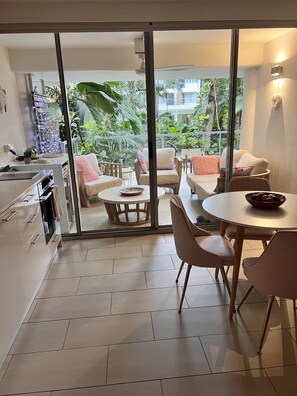 Enjoy meals in the dining area with a round table and comfortable seating, and step out to a balcony with a view of lush greenery.
