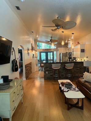 A spacious kitchen with a stone island, wooden flooring, and a ceiling fan.