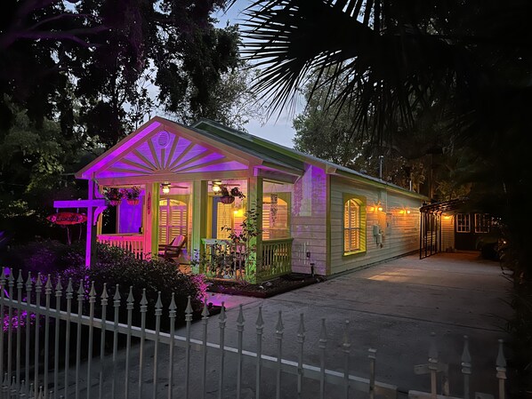 A small, single-story house with a porch, a small garden, and a fence. - Escondido Boutique Bungalow in Crystal Beach- Inquire for Seasonal Savings! (Palm Harbor)