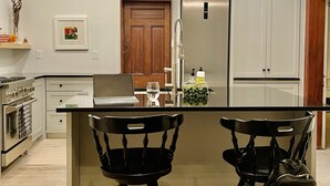 A modern kitchen with a central island, stainless steel appliances, and black chairs. - "The Cottage" Downtown Denver (Denver)