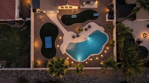 Vista aérea de uma propriedade residencial com piscina, duas banheiras de hidromassagem embutidas e área de estar com móveis para área externa.