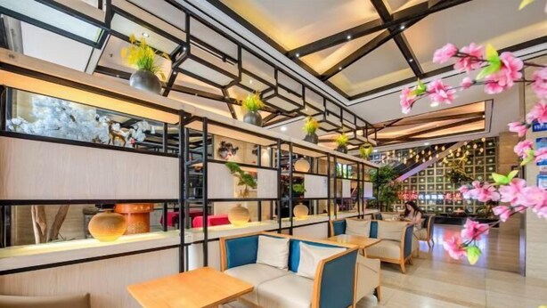 Un interior moderno con zonas de estar, estanterías con objetos decorativos y una escalera al fondo.