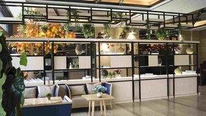 Un interior moderno con mostrador de recepción, zona de estar y estanterías con plantas.