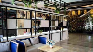 Un interior moderno con una zona de estar, una mesa de madera y estantes que exhiben varios objetos.