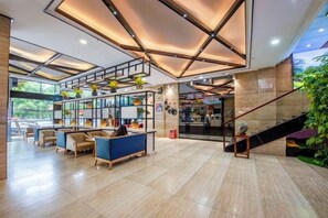 A spacious lobby with a staircase, seating areas, and a reception desk. - City Encounter Boutique Art Hotel (Zhuhai)