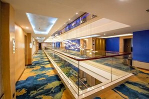 A hotel corridor with a glass railing, a patterned carpet, and a modern ceiling design. - City Encounter Boutique Art Hotel (Zhuhai)