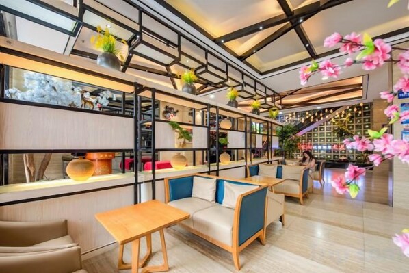 A modern interior with seating areas, shelves with plants, and a bar area. - City Encounter Boutique Art Hotel (Zhuhai)