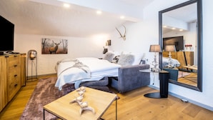 A bedroom with a bed, bedside table, lamp, mirror, and a deer antler decoration. - Apartment "Andy's Bergjuwel" with Mountain View, Wi-Fi & Balcony (Leutasch)