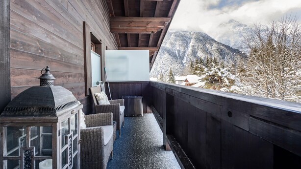 A wooden balcony with wicker furniture, a lantern, and a view of snow-covered mountains. - Apartment "Andy's Bergjuwel" with Mountain View, Wi-Fi & Balcony (Leutasch)