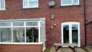 A brick house with a large window, a satellite dish, and a wooden bench. - The Nest, an Immaculate 3-Bed House in Walsall (Walsall)