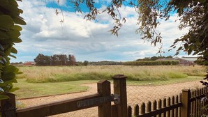 A wooden gate leading to a grassy field with a fence and a wire fence in the background. - Vineyard Cottage Sleeps 4 with Garden (Norwich)