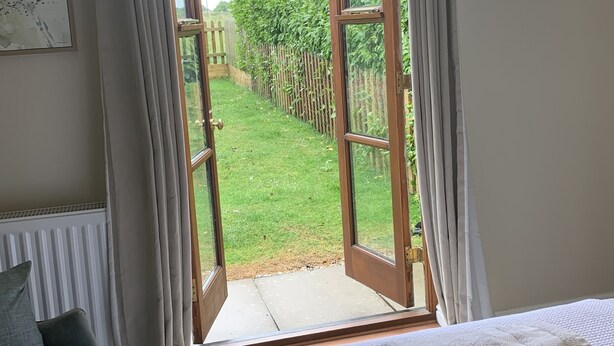 A bedroom with a large window, a bed, a chair, and a radiator. - Vineyard Cottage Sleeps 4 with Garden (Norwich)