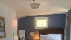 A bedroom with a wooden bed, a nightstand, a mirror, and a window. - Trip6 Historic Brick Home (Helena)