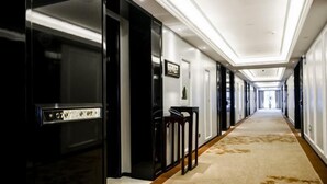Un pasillo de hotel con piso alfombrado, puertas de marco negro y pared de color claro.