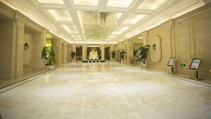 Un hall amplio con techo alto, suelo de mármol y columnas simétricas.