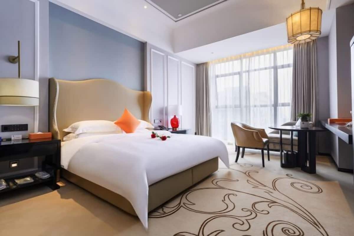Une chambre d’hôtel avec un grand lit, un bureau, une chaise et une lampe.