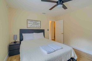 A bedroom with a bed, nightstand, and a ceiling fan. - Spacious Getaway ~ Heated LED Pool & Ping Pong (Minneola)