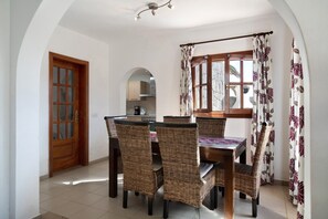 Un comedor con una mesa y sillas, una puerta de madera y vistas a la cocina.