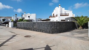 A coastal building with white walls, a stone wall, and a clear blue sky. - Villa Serendipity with Mountain View, Private Heated Pool & Wi-Fi (Playa Blanca)