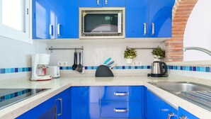 A kitchen with blue cabinets, a microwave, a coffee maker, and a sink.