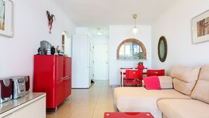 A modern living room with a red sofa, a red dining table, and a red cabinet.