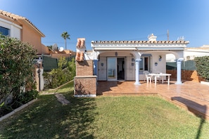 A house with a patio, a brick chimney, and a door leading to a covered area with a table and chairs.