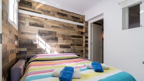 Una habitación de hotel con cama, un banco y pared de madera.