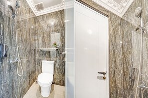 A bathroom with a marble wall, a toilet, a shower, and a white door. - OYO 90480 Sultan Guest House (Malang)