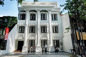 Un edificio blanco con columnas grandes y muchas ventanas, que presenta un letrero de casa de huéspedes.